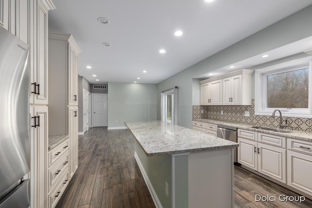 kitchen with tasteful backsplash, a center island, dark wood-type flooring, stainless steel appliances, and a sink