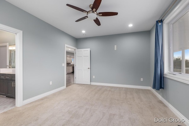 unfurnished bedroom with ensuite bath, light colored carpet, baseboards, and recessed lighting