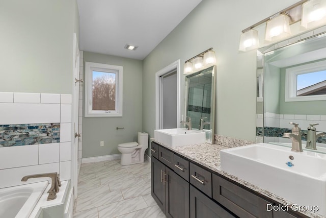full bath with a bath, toilet, a sink, and double vanity