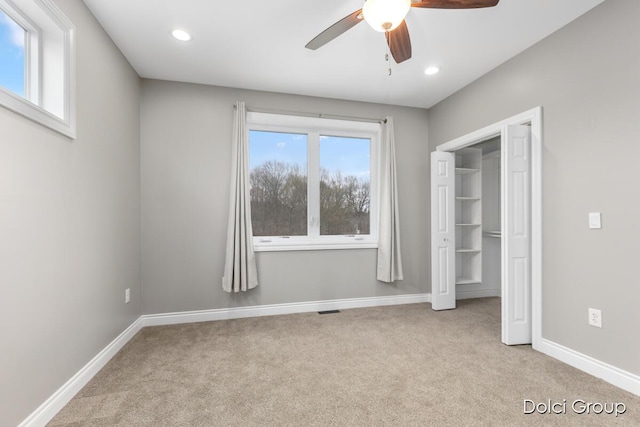 unfurnished bedroom with baseboards, multiple windows, and light colored carpet