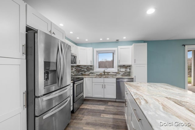 kitchen with light stone counters, a sink, plenty of natural light, and stainless steel appliances