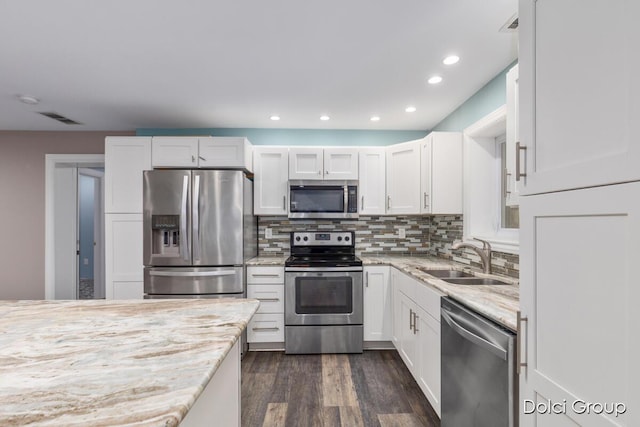 kitchen featuring light stone countertops, white cabinetry, visible vents, appliances with stainless steel finishes, and a sink