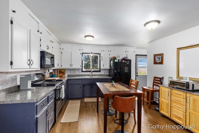 kitchen with wood finished floors, dark countertops, and black appliances