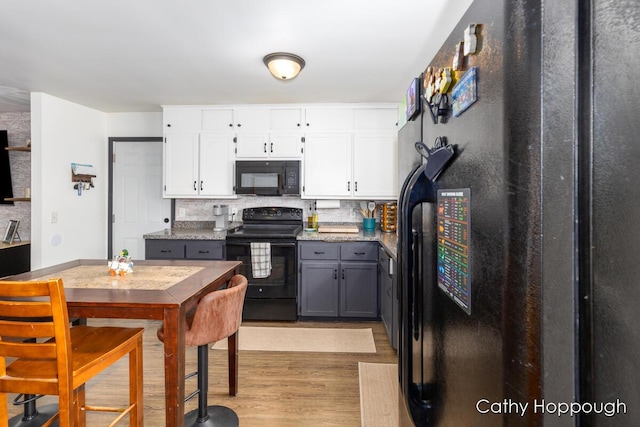 kitchen with backsplash, white cabinets, black appliances, and light wood finished floors