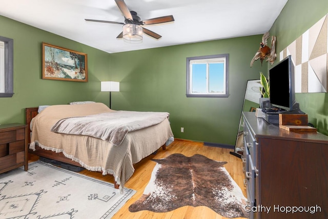bedroom featuring light wood finished floors, baseboards, and a ceiling fan