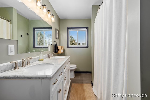 full bath with a sink, toilet, and double vanity