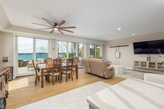 dining space with recessed lighting, light wood finished floors, a water view, and a ceiling fan