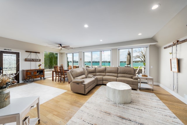 living room with light wood-style flooring, a water view, baseboards, recessed lighting, and ceiling fan