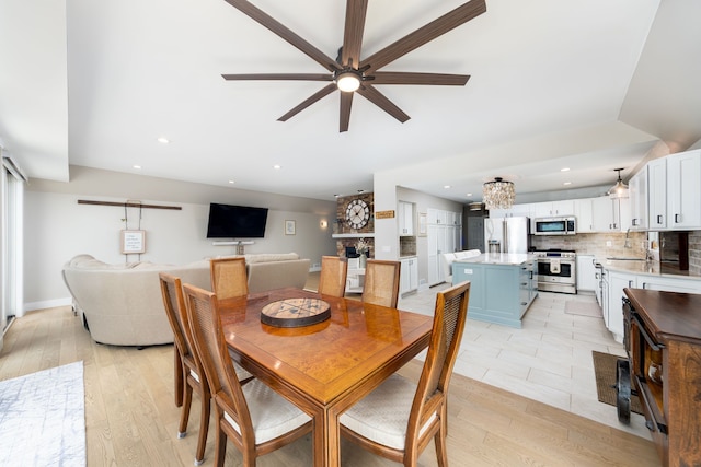dining space with recessed lighting, light wood finished floors, and ceiling fan with notable chandelier