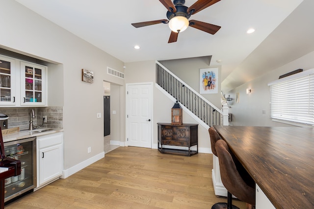office area with beverage cooler, wet bar, a sink, light wood-type flooring, and ceiling fan