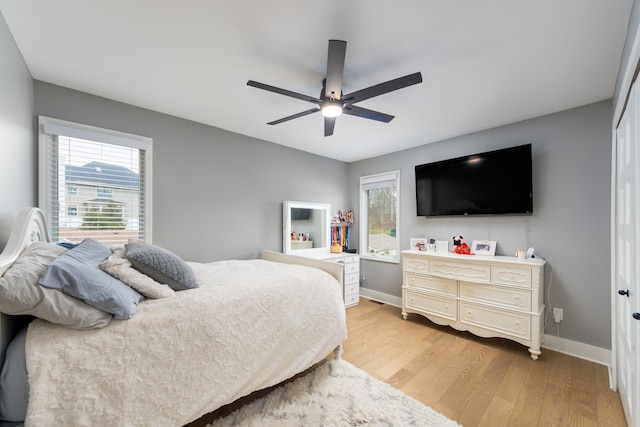 bedroom with light wood-type flooring, baseboards, ceiling fan, and multiple windows