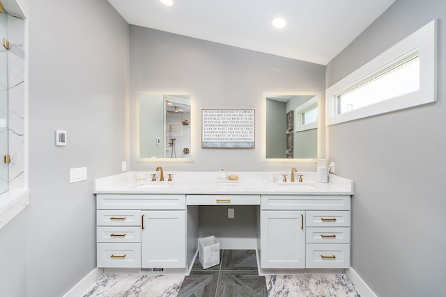 full bathroom with walk in shower, baseboards, a sink, and double vanity