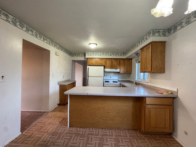 29318 Orvylle Dr, Warren, MI 48092 - kitchen featuring brown cabinets, a sink, a peninsula, under cabinet range hood, and white appliances