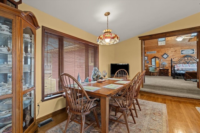 2745 Lari Ct, West Bloomfield, MI 48324 - dining room with lofted ceiling, wooden walls, visible vents, and wood finished floors
