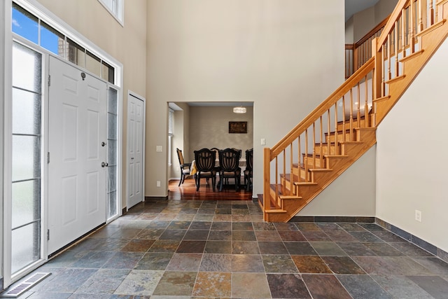 9025 Huron Bluffs Dr, White Lake, MI 48386 - foyer entrance with a healthy amount of sunlight, stone tile floors, baseboards, a towering ceiling, and stairs