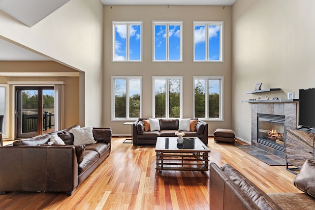 9025 Huron Bluffs Dr, White Lake, MI 48386 - living room featuring a fireplace, baseboards, a high ceiling, and hardwood / wood-style flooring