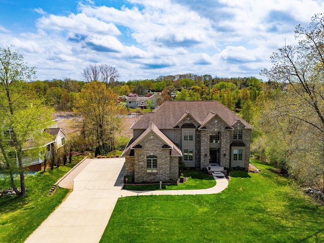 9025 Huron Bluffs Dr, White Lake, MI 48386 - view of front of house with stone siding, a view of trees, and a front yard