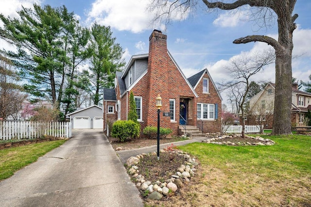 tudor house with an outbuilding, a detached garage, fence, a front lawn, and brick siding