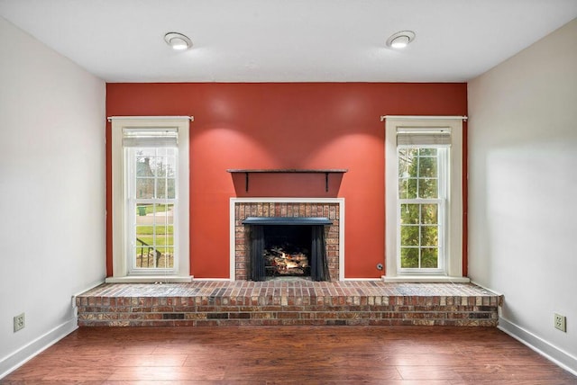 unfurnished living room with a fireplace, baseboards, and wood finished floors