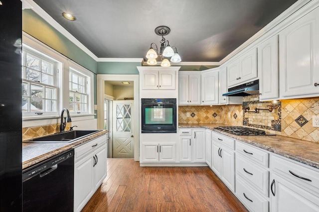 kitchen featuring backsplash, white cabinets, under cabinet range hood, black appliances, and a sink