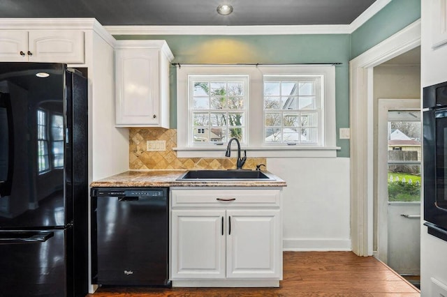 kitchen with tasteful backsplash, white cabinetry, black appliances, dark wood-style flooring, and a sink
