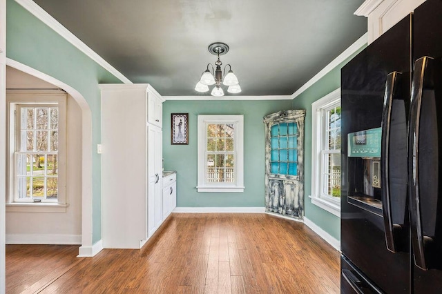 unfurnished dining area with wood finished floors, baseboards, and a notable chandelier