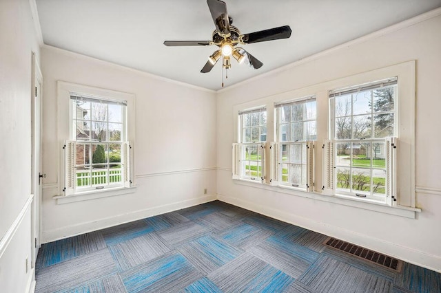 empty room featuring crown molding, visible vents, baseboards, and a ceiling fan