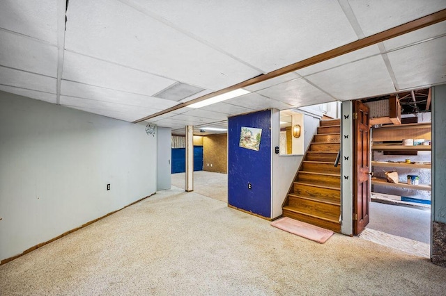 finished basement with stairs, carpet flooring, and a drop ceiling