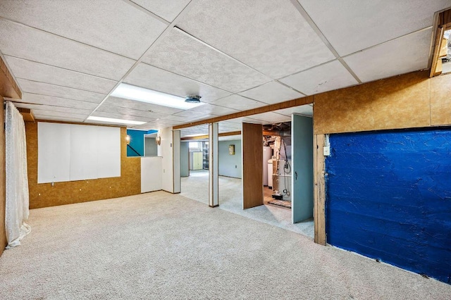 finished below grade area featuring a paneled ceiling and carpet flooring