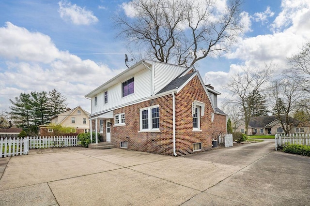 back of house featuring brick siding, fence, and a residential view