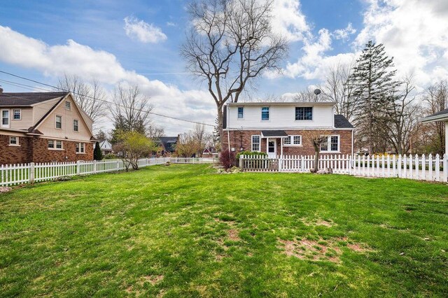 rear view of property with a yard, brick siding, and fence private yard
