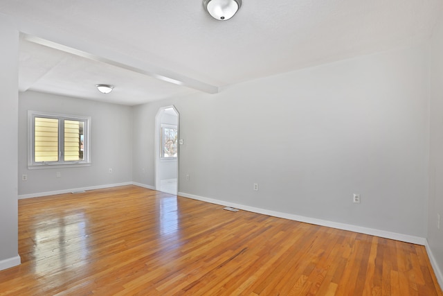 25763 Gibraltar Rd, Flat Rock, MI 48134 - spare room with light wood-style floors, arched walkways, baseboards, and beamed ceiling