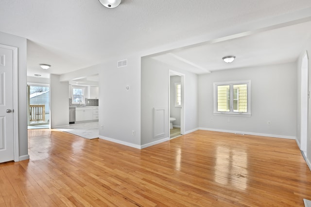 25763 Gibraltar Rd, Flat Rock, MI 48134 - unfurnished living room with a sink, baseboards, light wood-type flooring, and visible vents