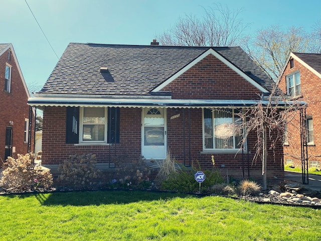 bungalow-style house featuring a front lawn, a shingled roof, and brick siding