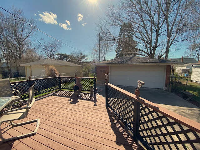 wooden deck featuring a garage, fence, and an outdoor structure