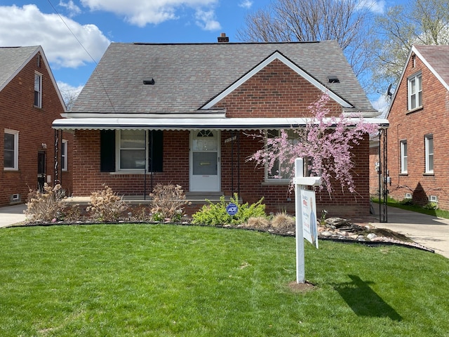 view of front of property with roof with shingles, a front lawn, covered porch, and brick siding