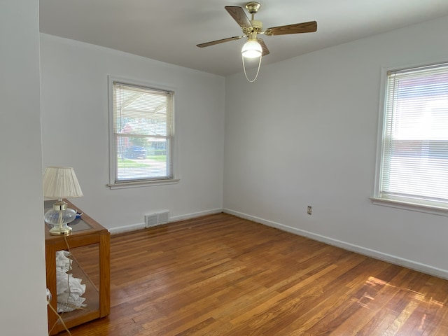 spare room with visible vents, wood finished floors, and a wealth of natural light
