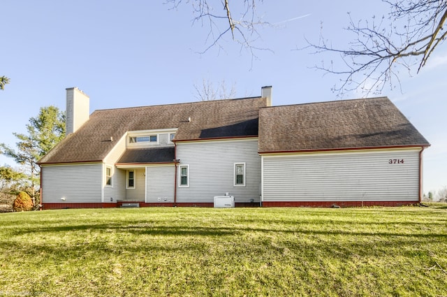 rear view of property featuring a chimney and a lawn
