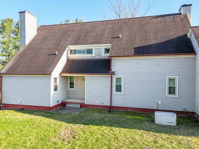 back of house featuring a chimney, roof with shingles, and a lawn
