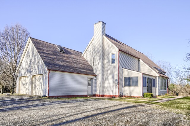 view of home's exterior with a chimney and a detached garage