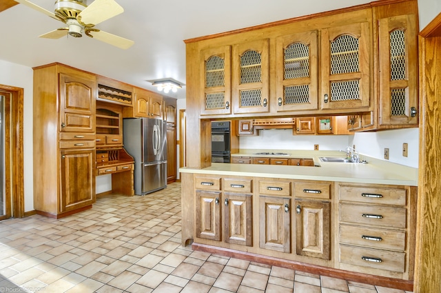 kitchen featuring gas cooktop, a sink, light countertops, and freestanding refrigerator