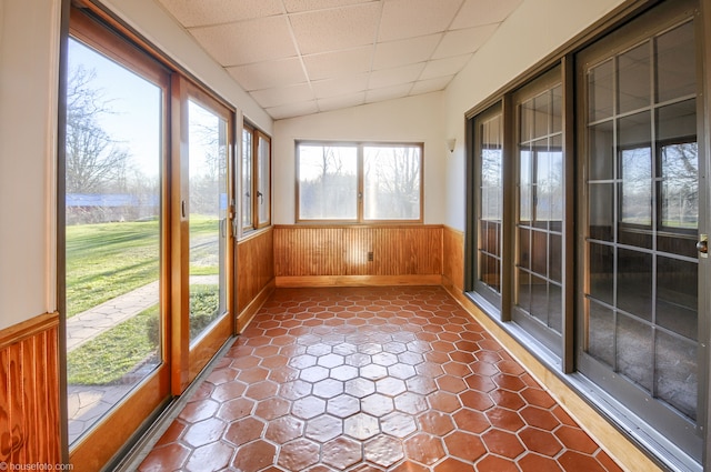 unfurnished sunroom with wainscoting, wood walls, and vaulted ceiling