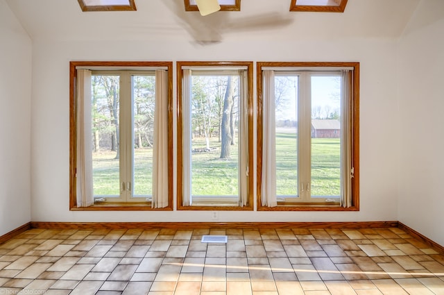 interior space with vaulted ceiling, a wealth of natural light, baseboards, and visible vents