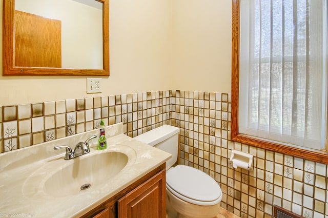 bathroom featuring tile walls, toilet, vanity, and a healthy amount of sunlight