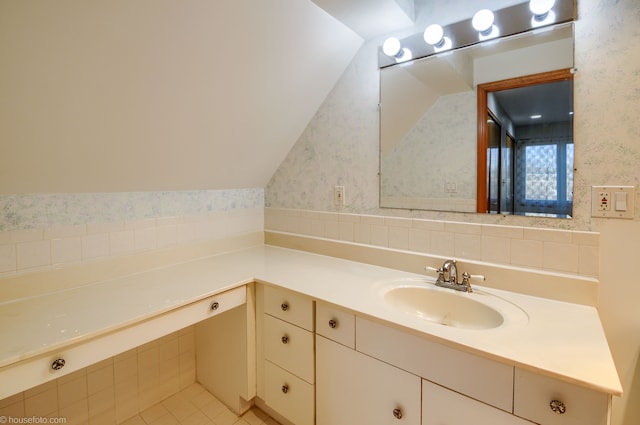bathroom featuring tile patterned flooring, vaulted ceiling, vanity, and wallpapered walls