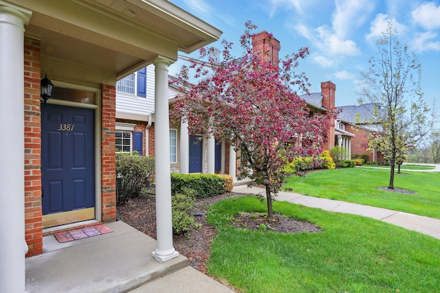 view of exterior entry with brick siding and a lawn