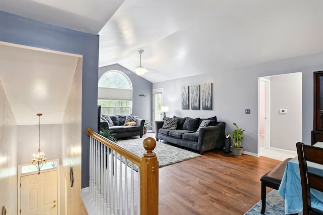living room with vaulted ceiling, wood finished floors, ceiling fan, baseboards, and a chandelier