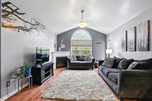 living room featuring vaulted ceiling, a ceiling fan, wood finished floors, and a fireplace