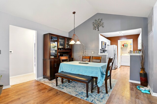 dining area with washer / clothes dryer, light wood-type flooring, and high vaulted ceiling