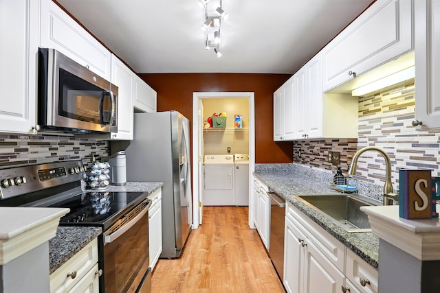 kitchen featuring stainless steel appliances, separate washer and dryer, a sink, white cabinetry, and light wood finished floors